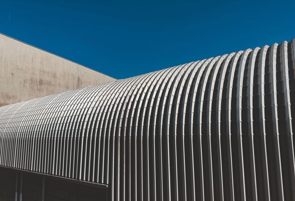 A sleek and modern corrugated metal facade with repeating stripes against a clear blue sky.