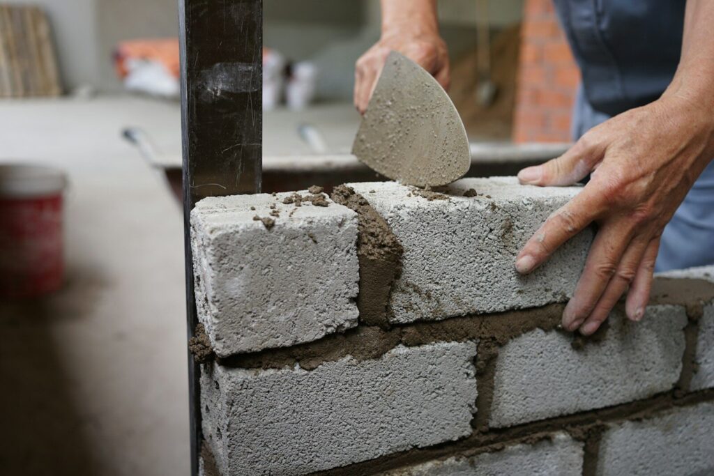 a person is putting cement on a brick wall