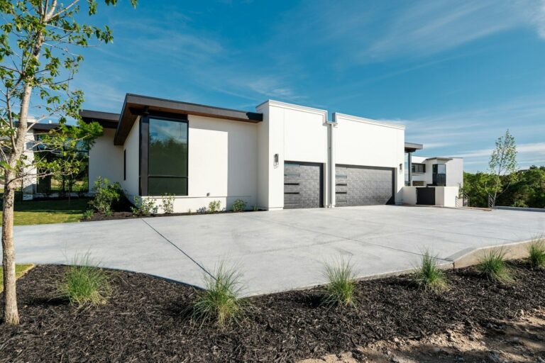 Modern white house, two garage doors, and concrete driveway