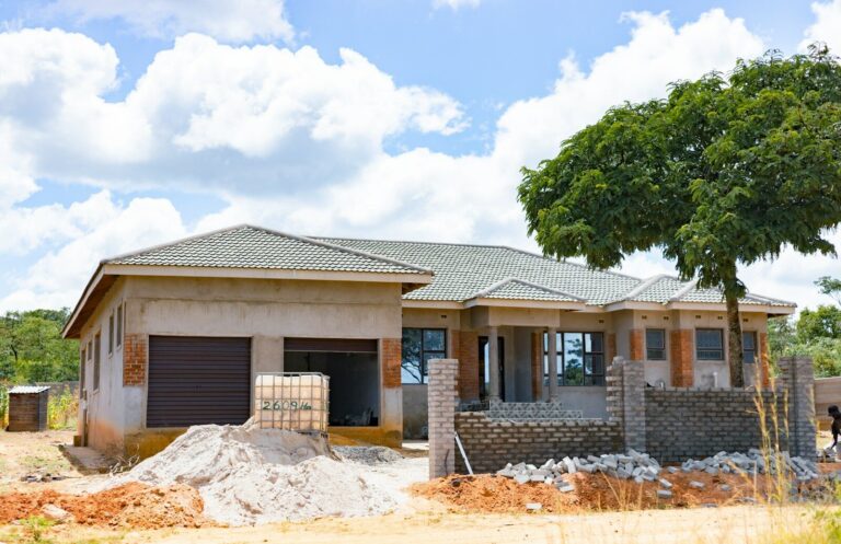 A house under construction with a tiled roof and brick accents near a tree